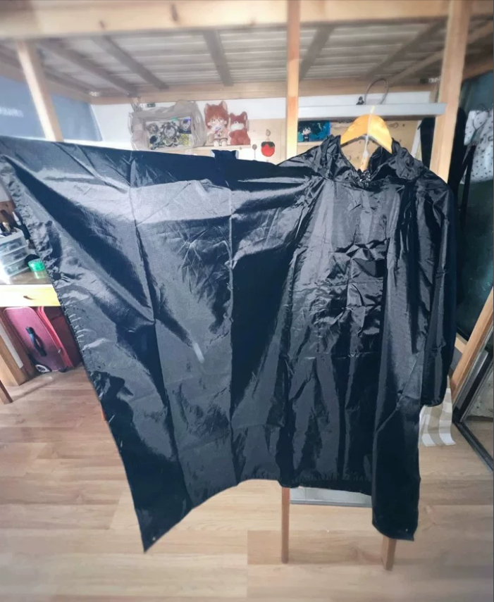 Regnponcho sort på model med rygsæk